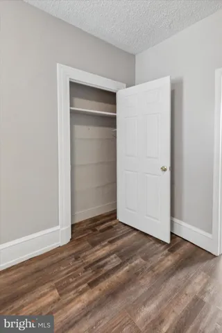an empty room with wooden floor & closet area