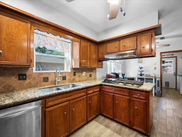 a kitchen with stainless steel appliances granite countertop wooden cabinets and a sink
