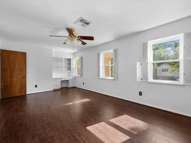 a view of an empty room with a window and wooden floor