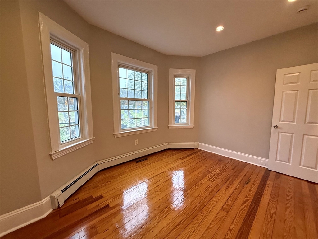 89 Grove Street, Unit 89 Belmont, MA 02478 - Photo 17 of 27 an empty room with wooden floor and windows