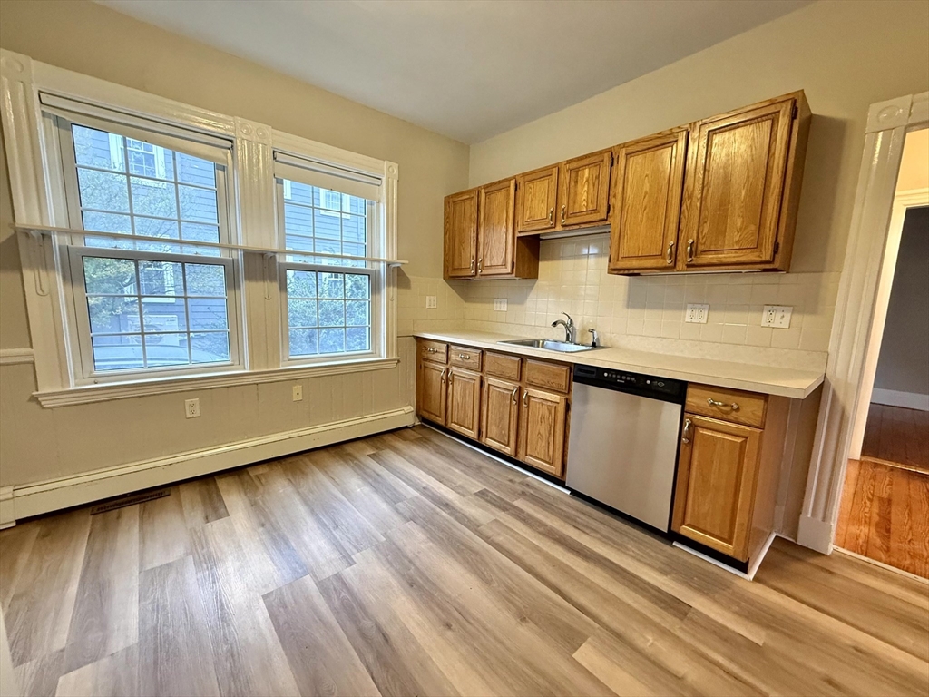89 Grove Street, Unit 89 Belmont, MA 02478 - Photo 4 of 27 a view of a kitchen counter top space a sink wooden floor and a window