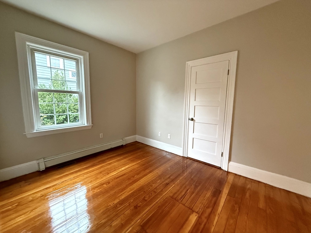 89 Grove Street, Unit 89 Belmont, MA 02478 - Photo 8 of 27 an empty room with wooden floor and windows