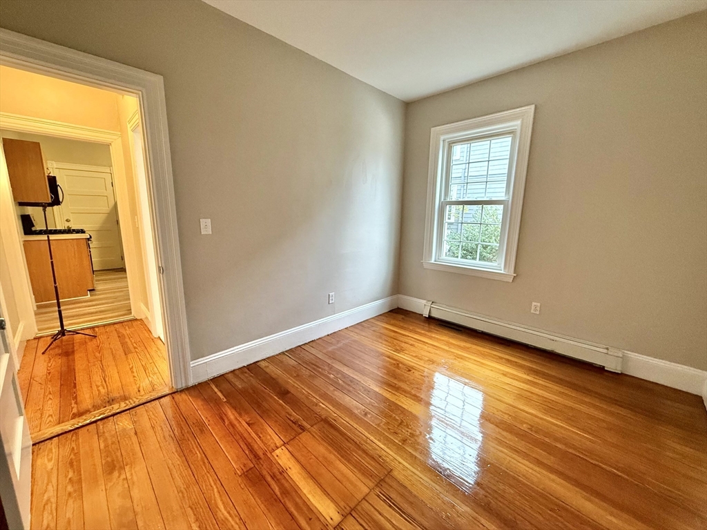 89 Grove Street, Unit 89 Belmont, MA 02478 - Photo 9 of 27 an empty room with wooden floor and windows
