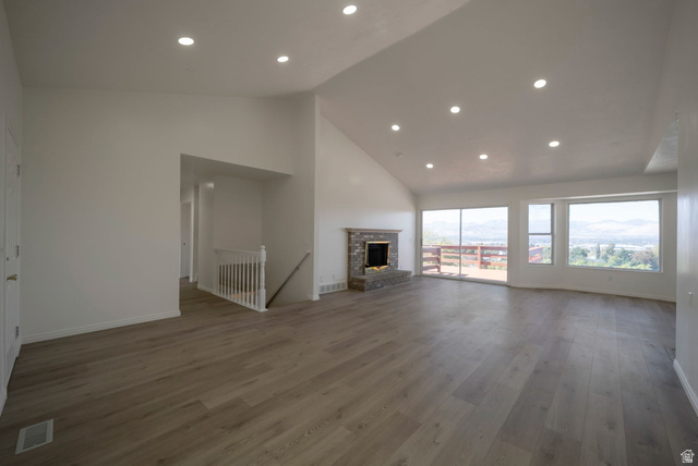 11922 Bluff View Drive Sandy, UT 84092 - Photo 4 of 30 Unfurnished living room featuring a high ceiling, recessed lighting, dark wood-style flooring, and a fireplace