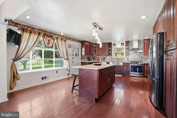 a kitchen with stainless steel appliances granite countertop a refrigerator a stove a sink and a dining table with wooden floor