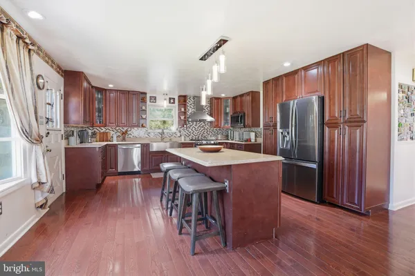 a kitchen with stainless steel appliances granite countertop wooden cabinets a sink and dishwasher a stove with wooden floor