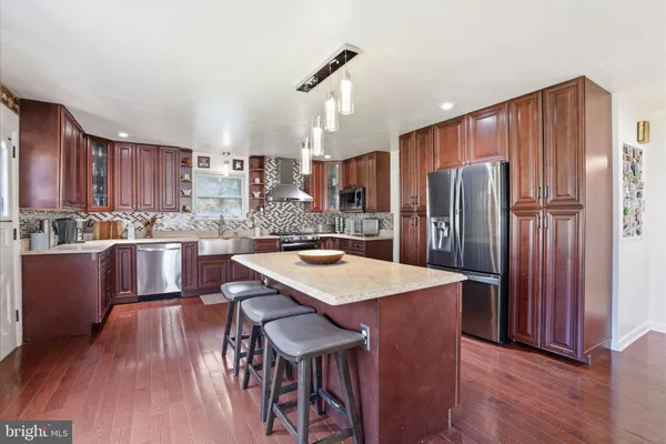 a kitchen with stainless steel appliances granite countertop a refrigerator a stove a sink dishwasher and a dining table with wooden floor