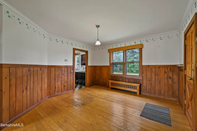 a view of an empty room with a window and wooden floor