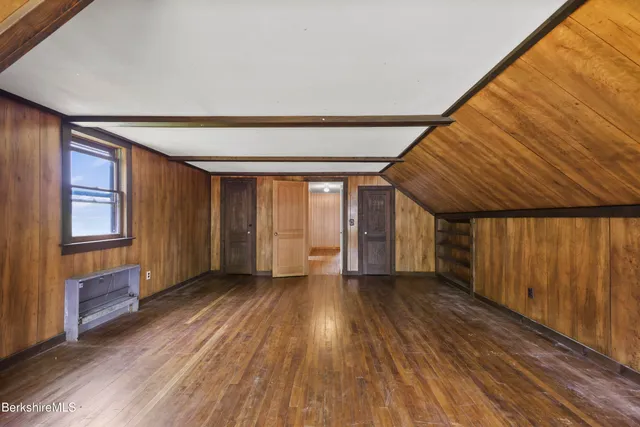a view of an empty room with wooden floor and windows