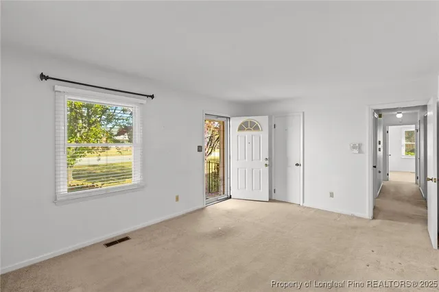 a view of an empty room with window and closet area