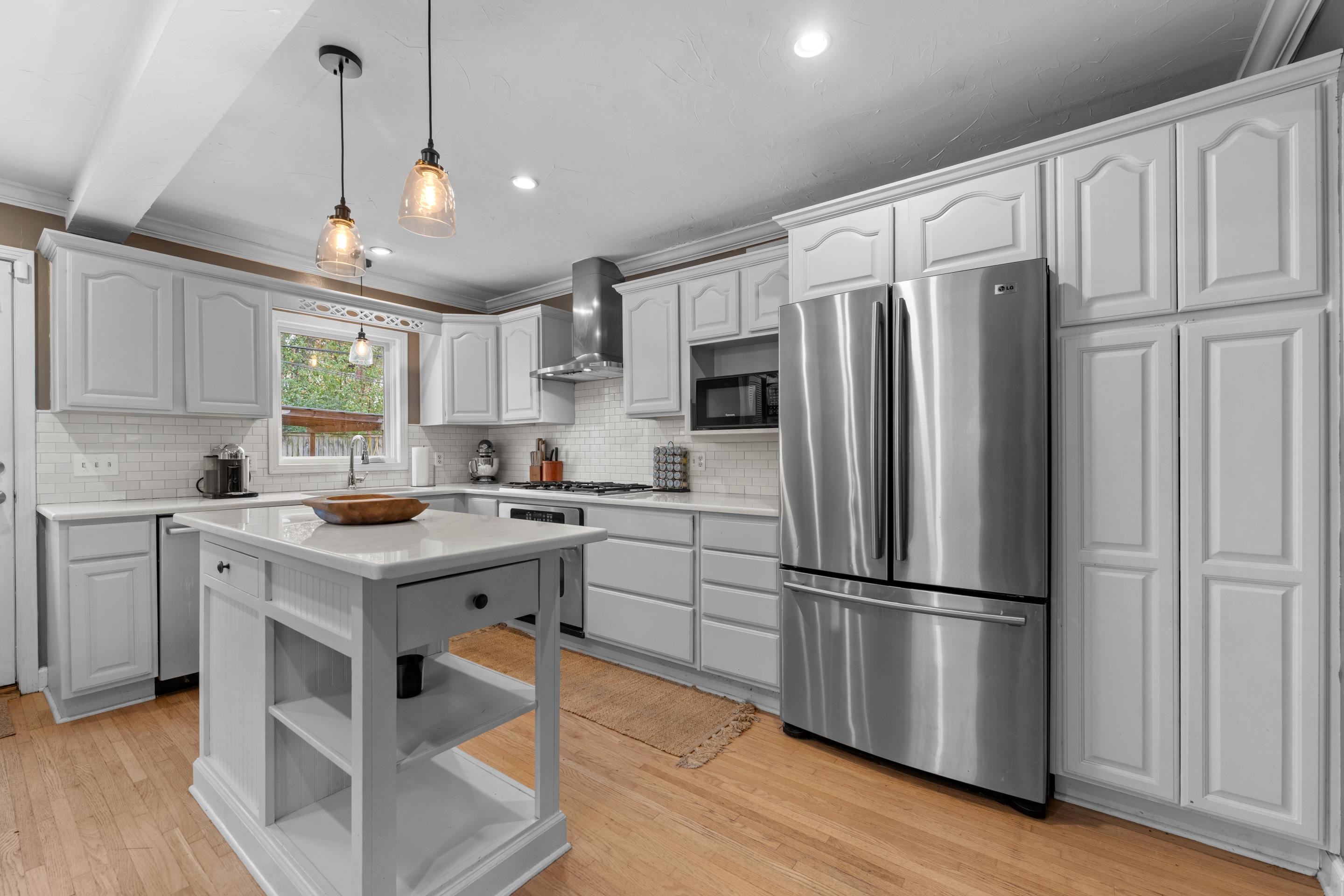 400 Rosser Road Memphis, TN 38120 - Photo 3 of 26 a kitchen with granite countertop a refrigerator a sink dishwasher a stove and white cabinets with wooden floor