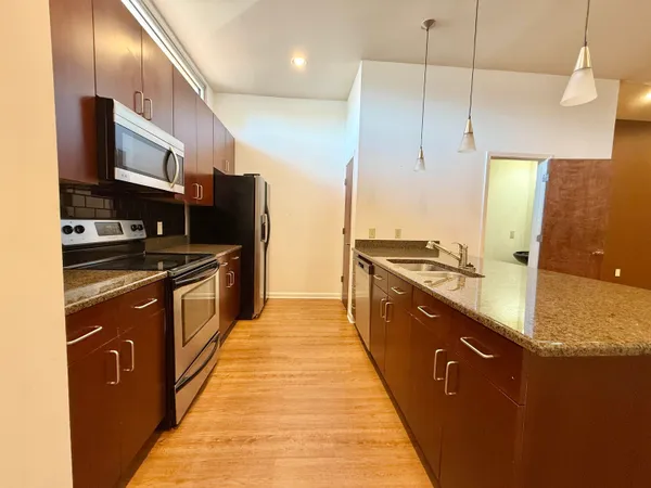 a large kitchen with stainless steel appliances granite countertop a stove a sink and a refrigerator