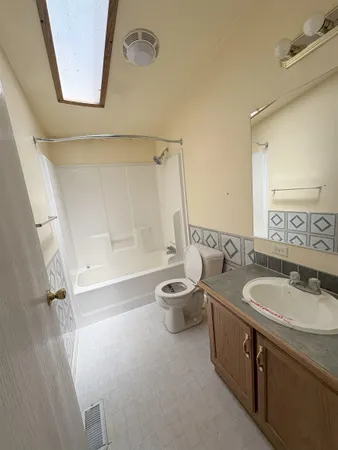 a bathroom with a granite countertop sink a toilet a mirror and shower