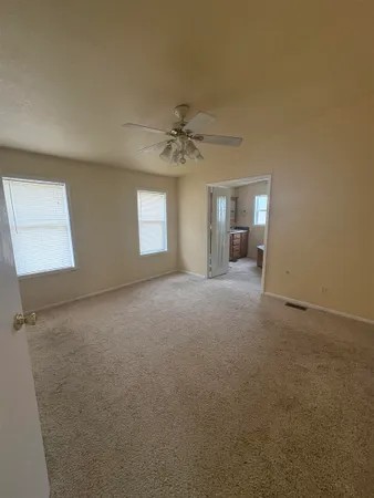 an empty room with chandelier fan and windows