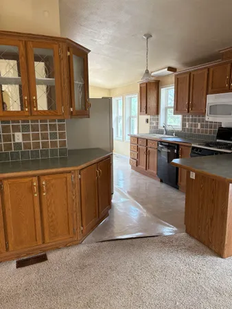 a kitchen with stainless steel appliances granite countertop a stove a sink dishwasher and a microwave oven with large wooden cabinets