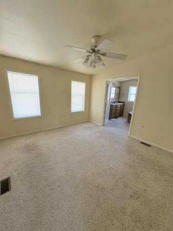 an empty room with windows and fan