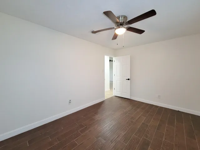 an empty room with wooden floor and ceiling fan
