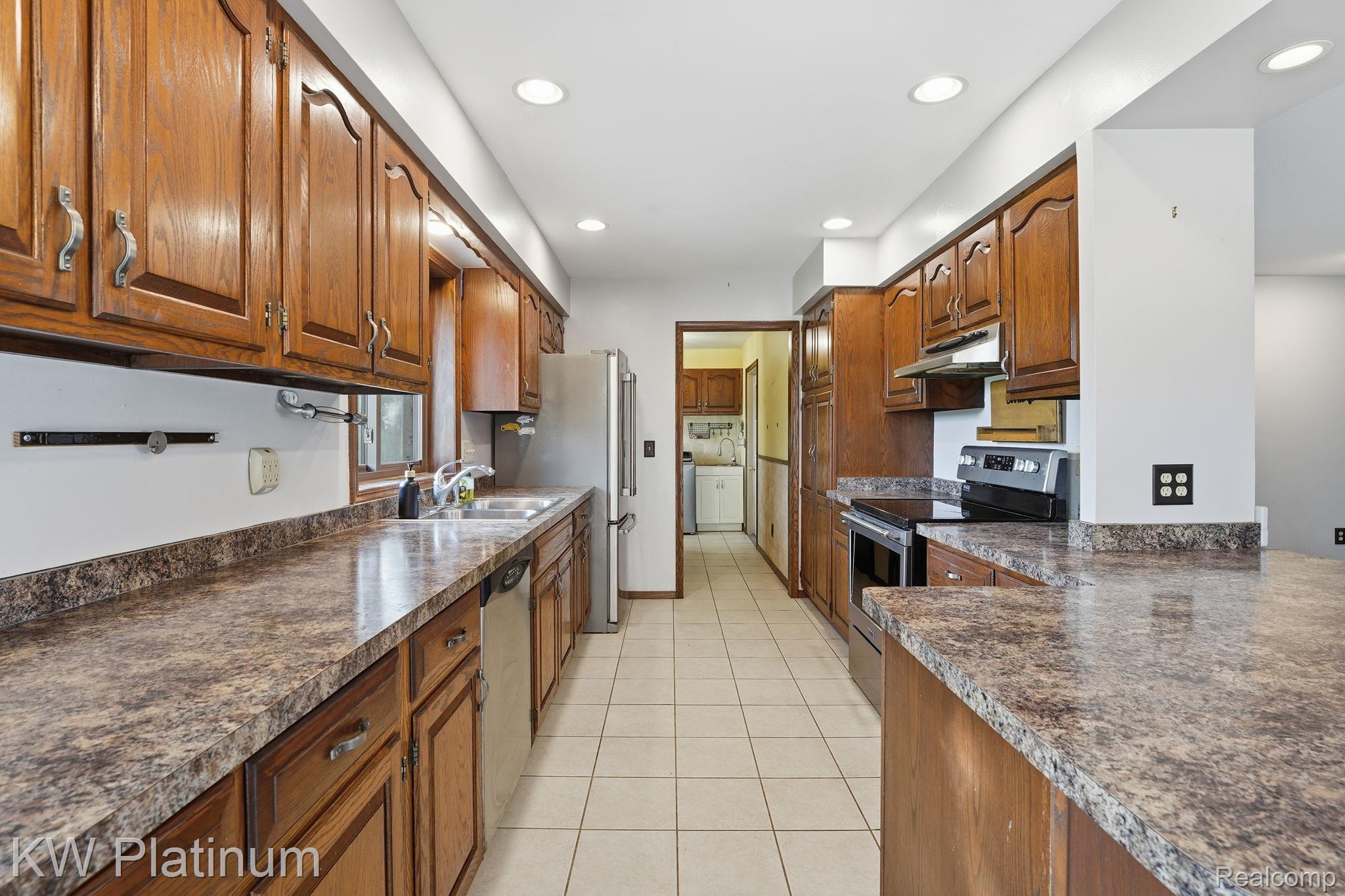 7383 Fisher Road Jeddo, MI 48032 - Photo 9 of 40 Kitchen with appliances with stainless steel finishes, brown cabinetry, recessed lighting, dark countertops, and light tile patterned floors