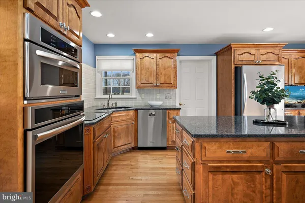 a kitchen with stainless steel appliances granite countertop a refrigerator a stove a sink and a refrigerator