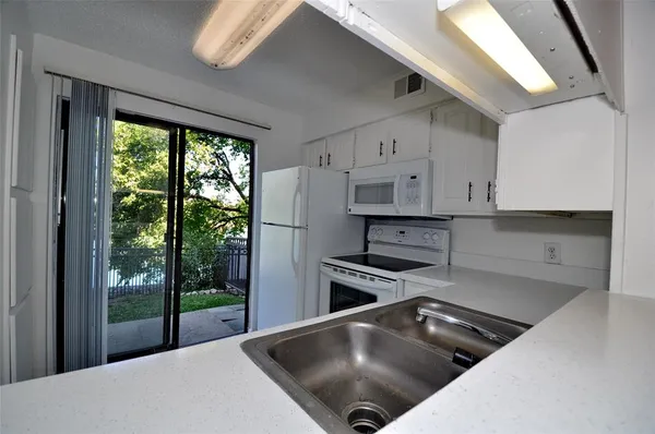 a kitchen with stainless steel appliances granite countertop a stove a refrigerator a sink and white cabinets with wooden floor