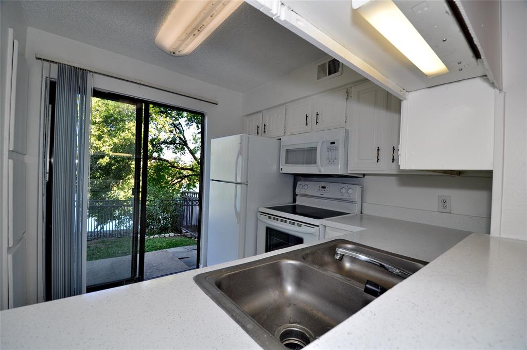 2610 Lakehill Lane, Unit 6B Carrollton, TX 75006 - Photo 16 of 18 a kitchen with stainless steel appliances granite countertop a stove a refrigerator a sink and white cabinets with wooden floor