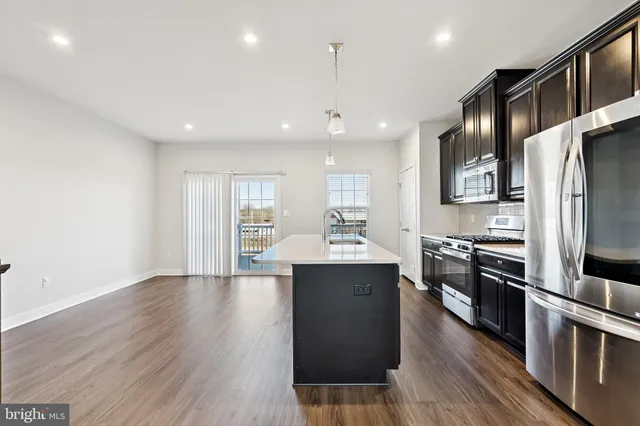 a kitchen with stainless steel appliances granite countertop a refrigerator a sink dishwasher a stove and white countertops with wooden floor