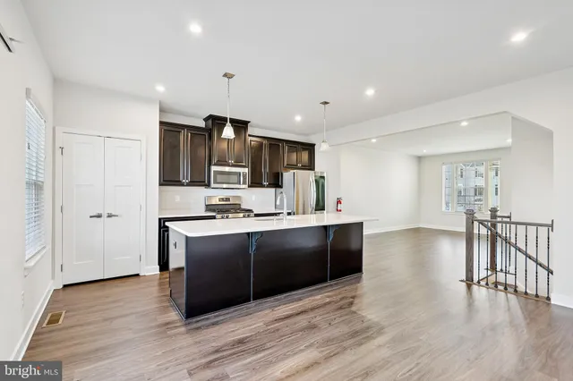 a view of kitchen with stainless steel appliances granite countertop a stove top oven a sink dishwasher a dining table and chairs with wooden floor