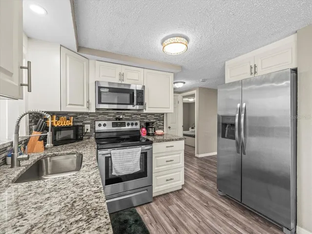 a kitchen with stainless steel appliances granite countertop a refrigerator stove and sink