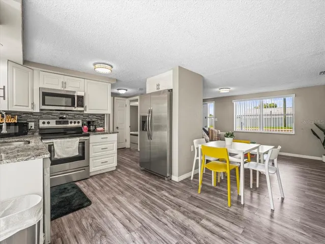 a kitchen with stainless steel appliances kitchen island granite countertop a dining table chairs and granite counter tops