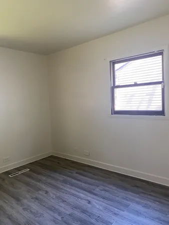 an empty room with wooden floor and a window