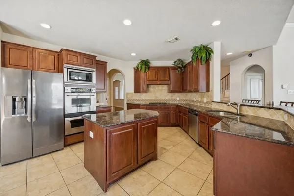 a kitchen with stainless steel appliances granite countertop a sink and a refrigerator