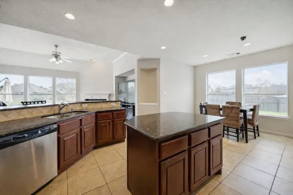 a kitchen with kitchen island granite countertop a stove a sink a dining table and chairs