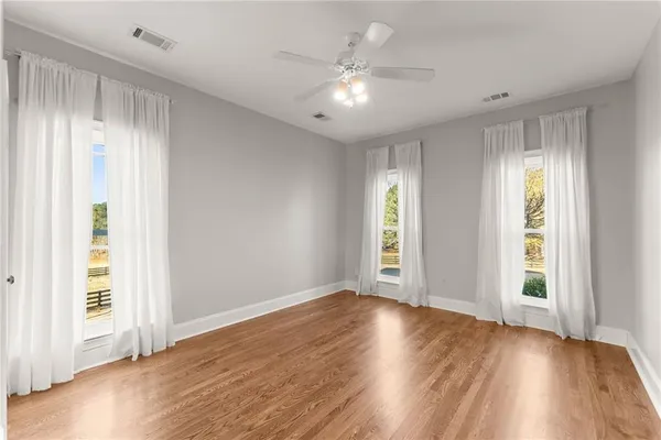 an empty room with a chandelier fan and windows