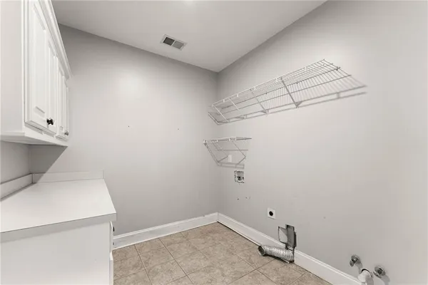 an empty room with a chandelier fan and windows