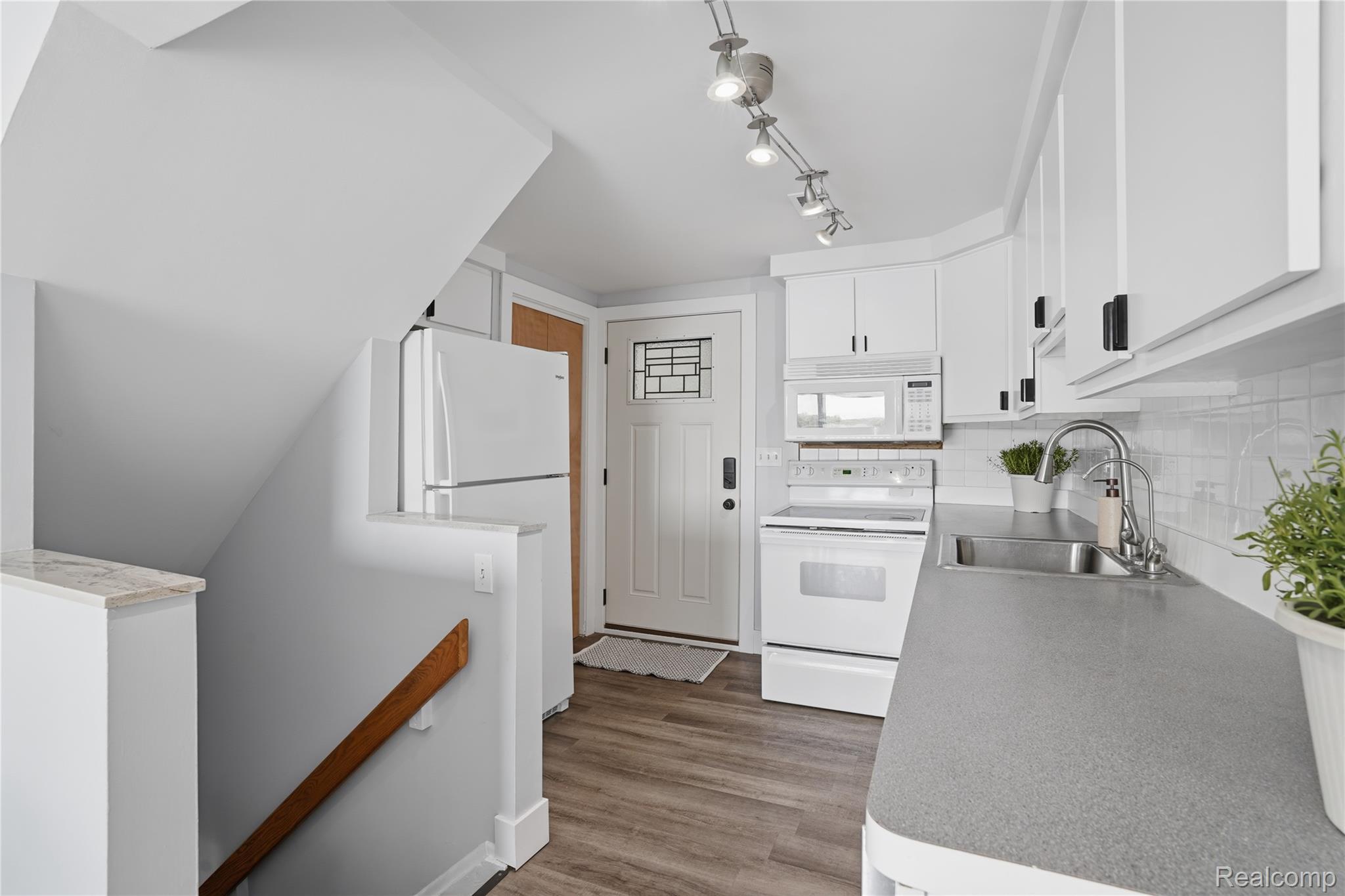 7217 Andersonville Road Clarkston, MI 48346 - Photo 13 of 65 Compact kitchen featuring white cabinetry with dark hardware, a stainless steel sink, and gray countertops