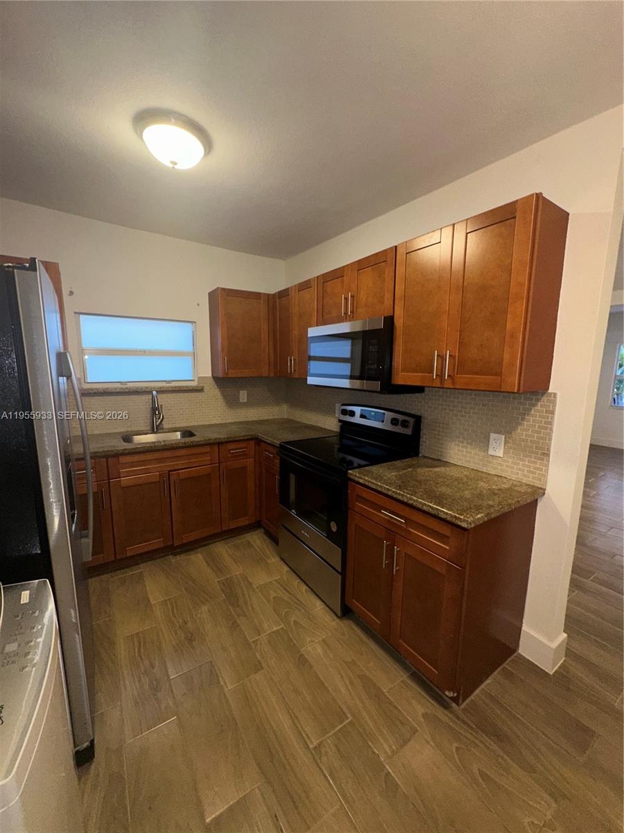 3123 Northwest 22nd Court, Unit A Miami, FL 33142 - Photo 11 of 18 a kitchen with stainless steel appliances granite countertop a stove a sink and a refrigerator