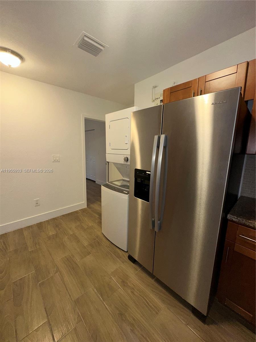 3123 Northwest 22nd Court, Unit A Miami, FL 33142 - Photo 13 of 18 a view of a refrigerator in kitchen and an empty room with wooden floor