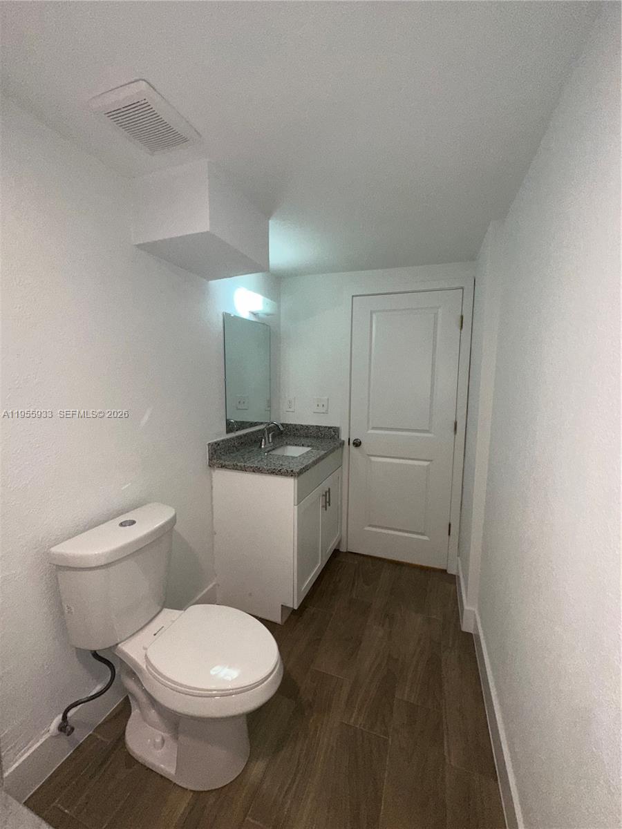 3123 Northwest 22nd Court, Unit A Miami, FL 33142 - Photo 18 of 18 a bathroom with a toilet sink and mirror