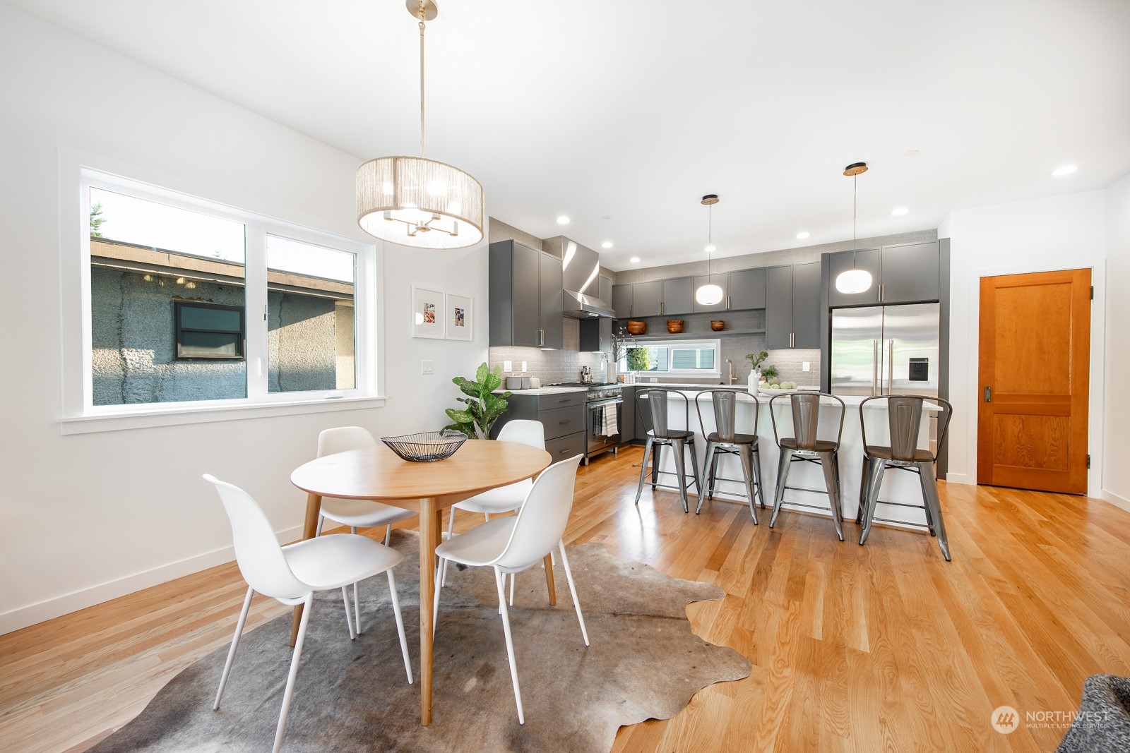3649 Francis Avenue North, Unit A Seattle, WA 98103 - Photo 14 of 35 a dining room with wooden floor a chandelier a wooden table and chairs
