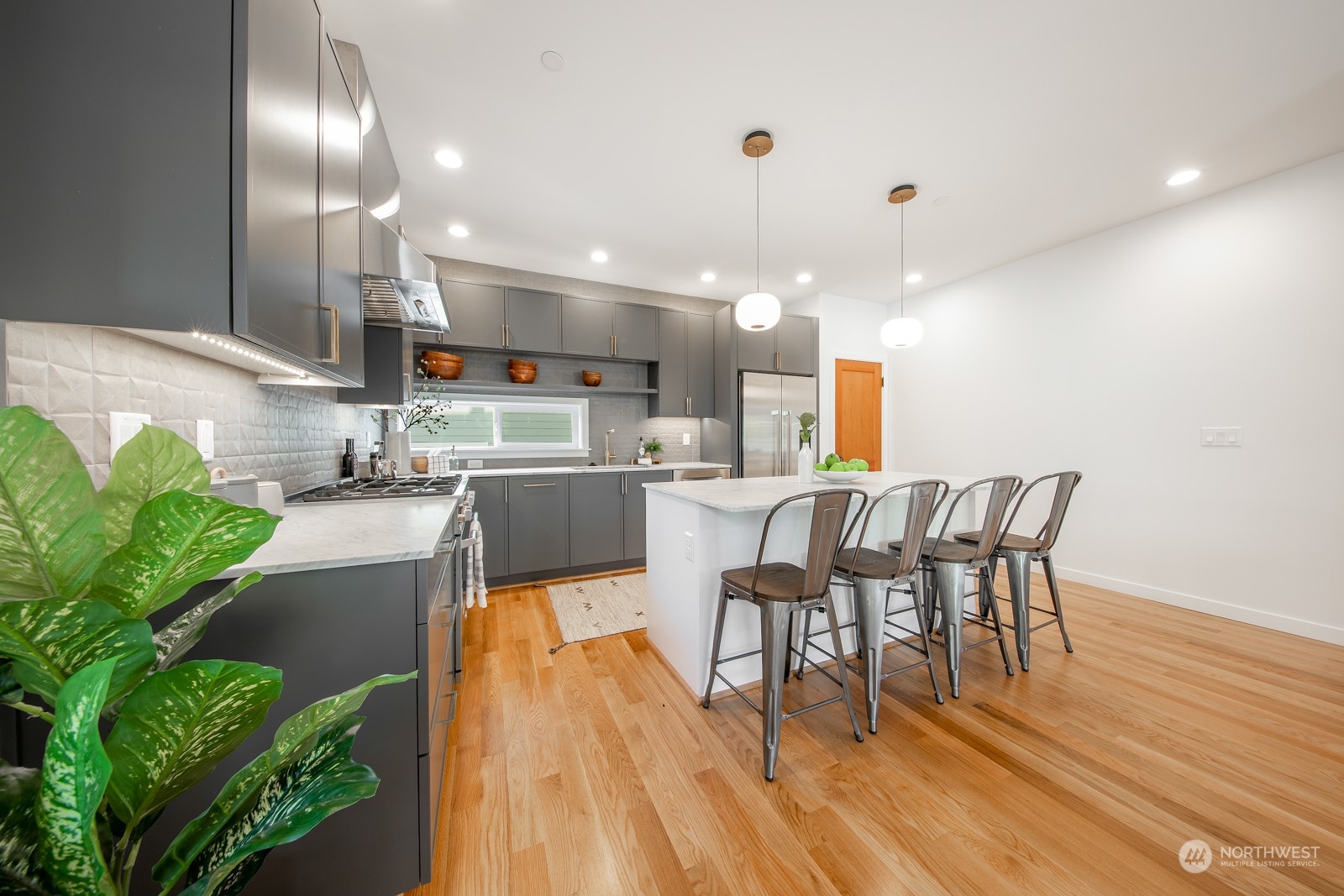3649 Francis Avenue North, Unit A Seattle, WA 98103 - Photo 8 of 35 a kitchen with stainless steel appliances kitchen island granite countertop a table chairs in it and a wooden floors