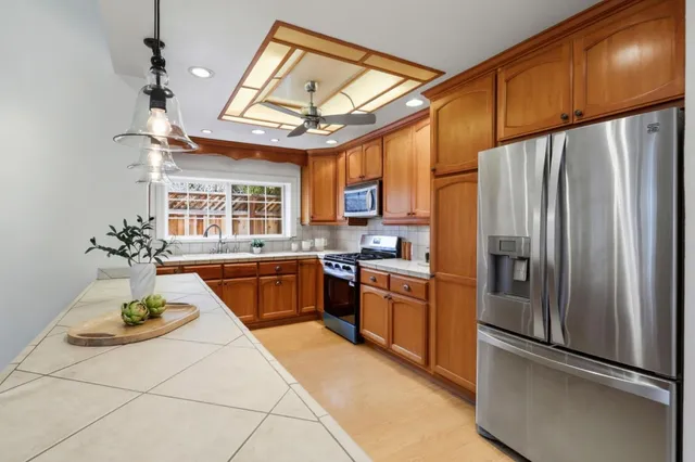 a kitchen with stainless steel appliances granite countertop a refrigerator a stove and a sink with cabinets
