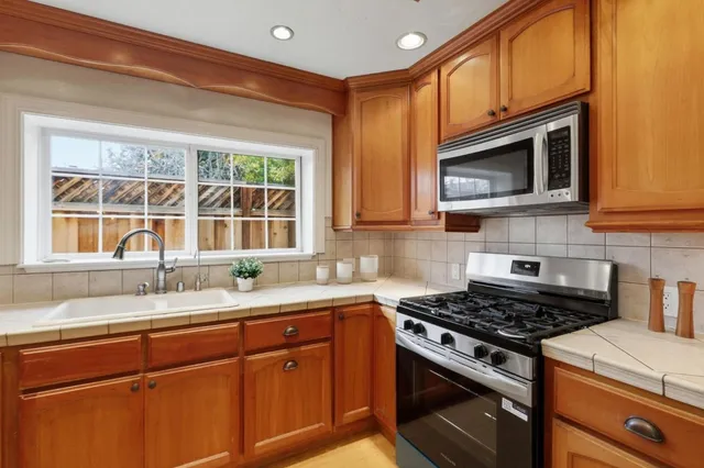 a kitchen with stainless steel appliances granite countertop white cabinets stove top oven and sink
