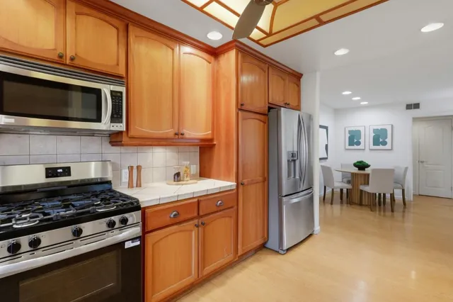 a kitchen with stainless steel appliances granite countertop a stove top oven a refrigerator and a microwave