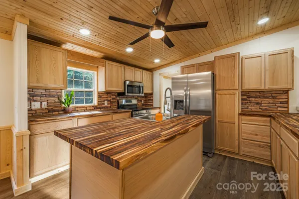 a kitchen with stainless steel appliances a refrigerator a stove a sink cabinets and a dining table