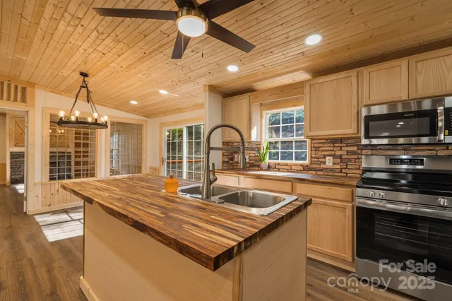 a kitchen with stainless steel appliances granite countertop a sink a stove and a wooden floors