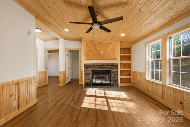a view of an empty room with wooden floor fireplace and a window