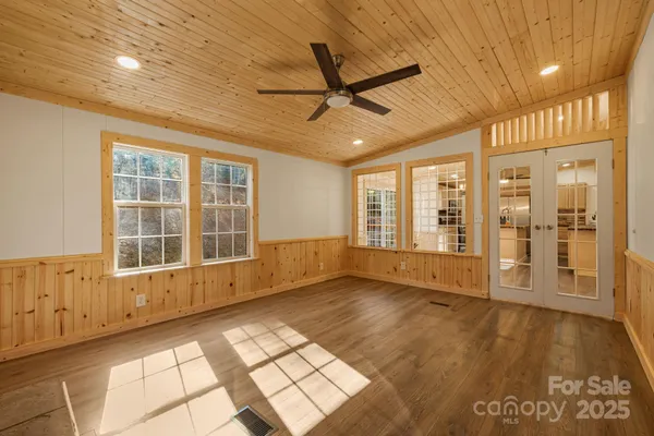 a view of an empty room with a window and wooden floor
