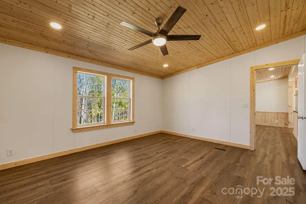 an empty room with wooden floor fan and windows