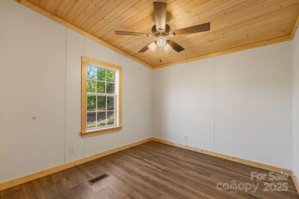 an empty room with wooden floor fan and windows