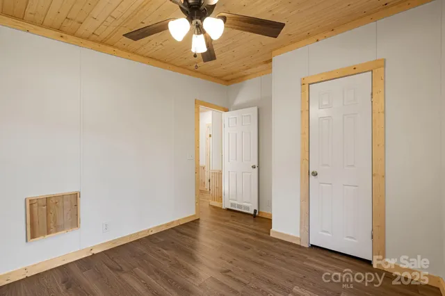 an empty room with wooden floor closet and ceiling fan